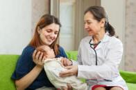 Nurse examining baby sitting on mother's lap